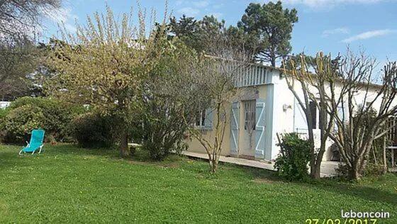 une maison blanche avec une chaise bleue dans une cour dans l'établissement gite de France, à Saint-Cyprien
