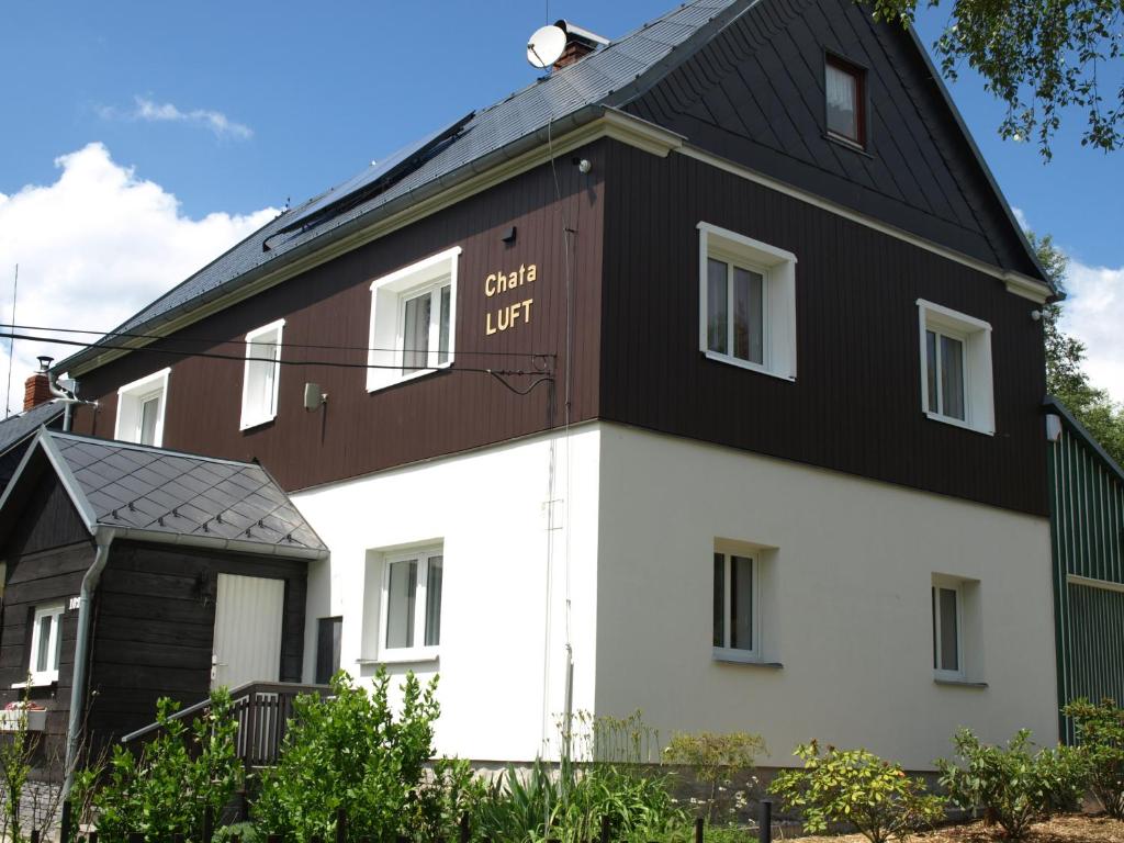 a white and brown house with a black roof at Guest House LUFT Sněžník in Sněžnik