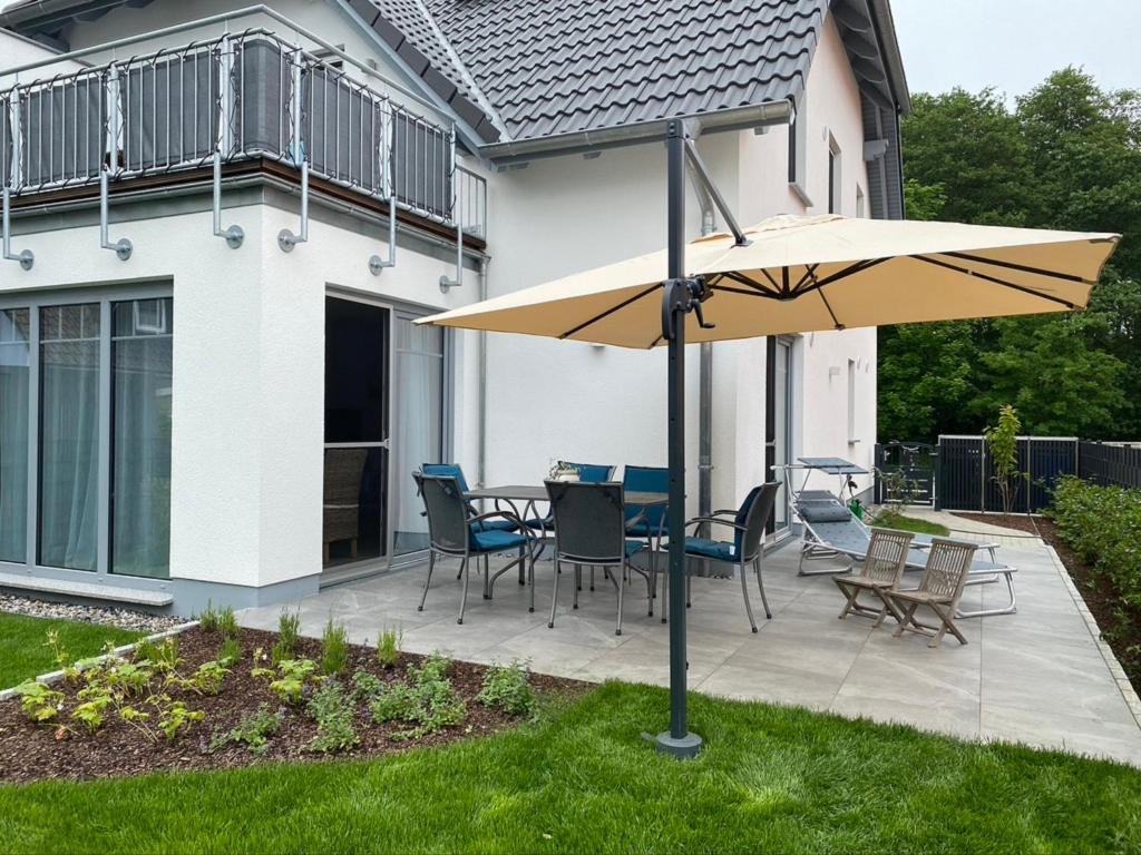 patio ze stołem, krzesłami i parasolem w obiekcie Inselhafen w mieście Juliusruh