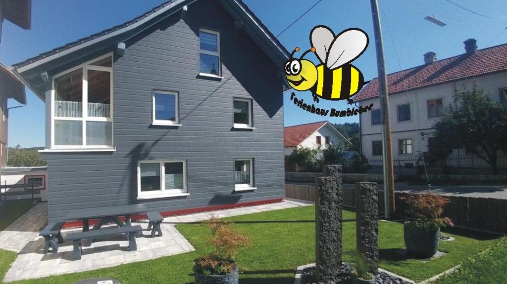 Una casa con una señal de abeja en el costado. en Ferienhaus Bumblebee im Allgäu en Eggenthal