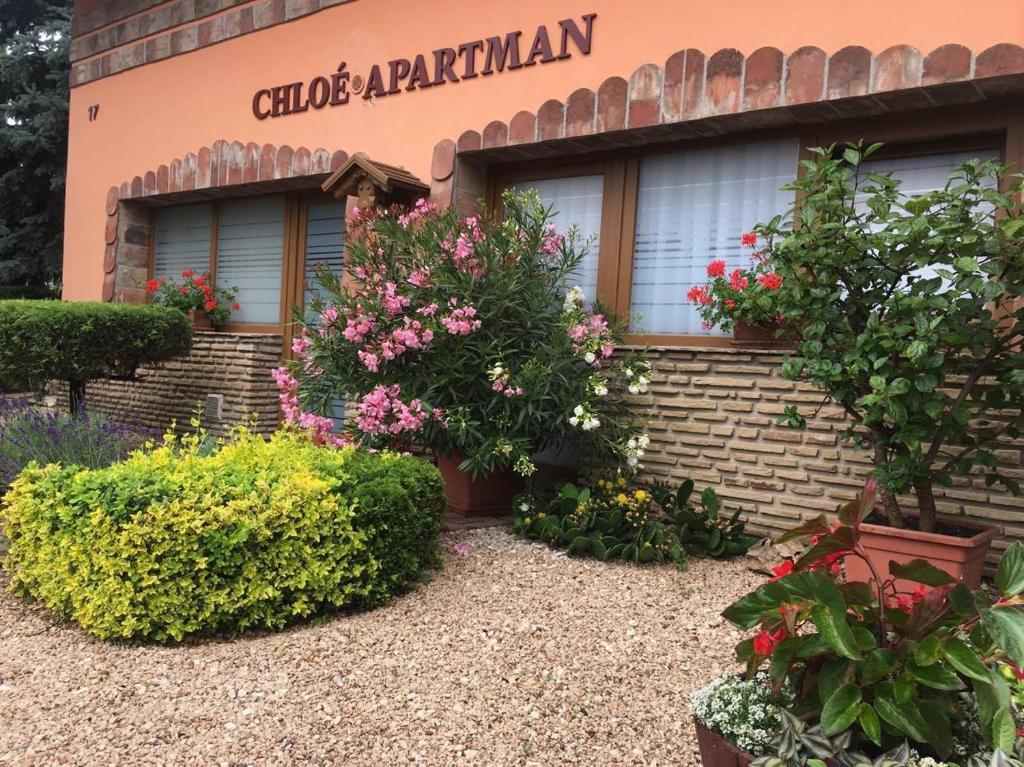 un edificio con flores y plantas delante de él en Chloe Apartman, en Szigetvár