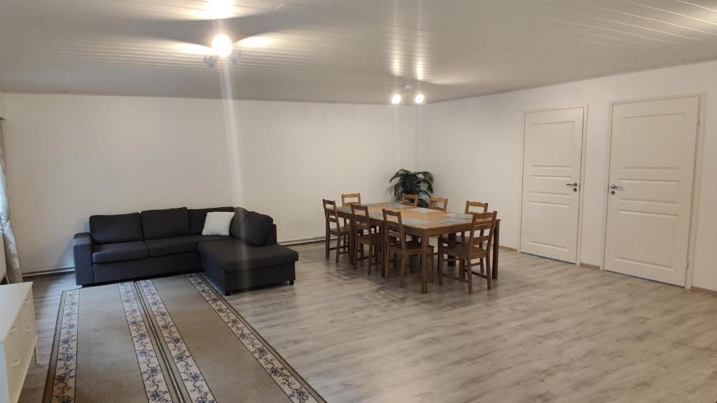 ein Wohnzimmer mit einem Tisch und einem schwarzen Sofa in der Unterkunft Apartments, 4 rooms + sauna in Kajaani