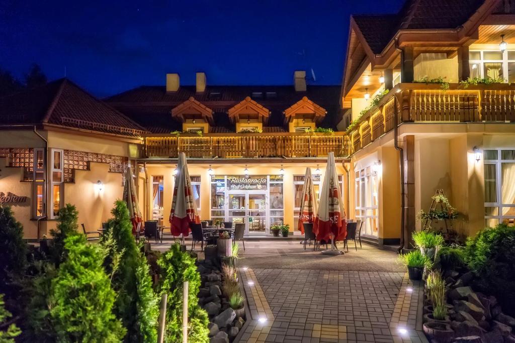 ヴィスワにあるHotel Pod Gołębiemの夜間にパラソルとパティオを利用できるホテル