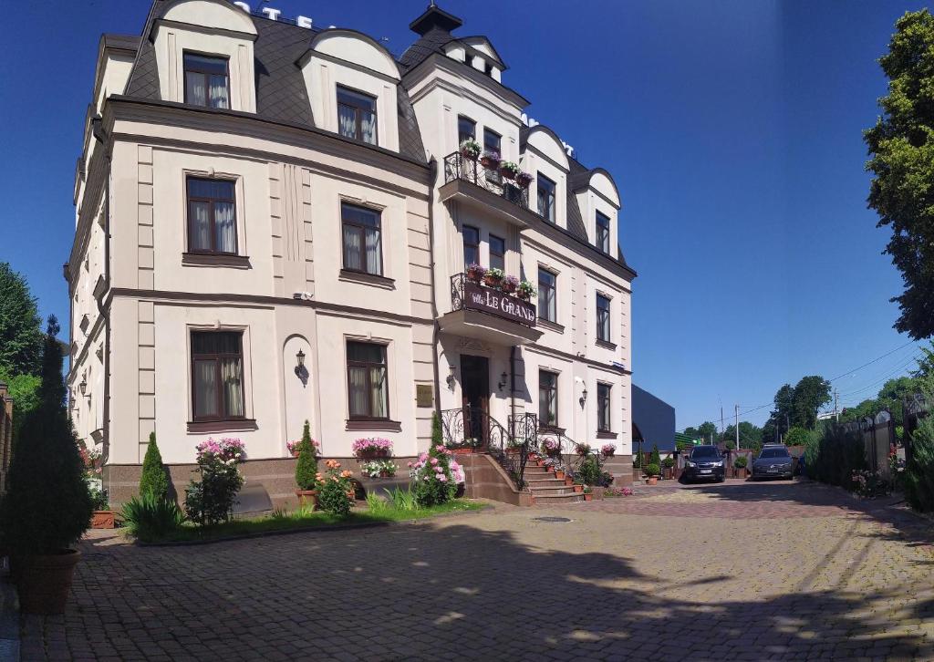 ボルィースピリにあるVLG Hotelの通りに面した白い大きな建物で、窓とバルコニーが付いています。
