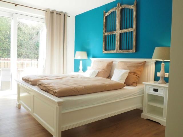 1 dormitorio con cama blanca y pared azul en Lauras Weinherberge, en Leinsweiler