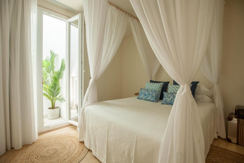 ein Schlafzimmer mit einem Himmelbett und einem Fenster in der Unterkunft Ana´s House in Setúbal