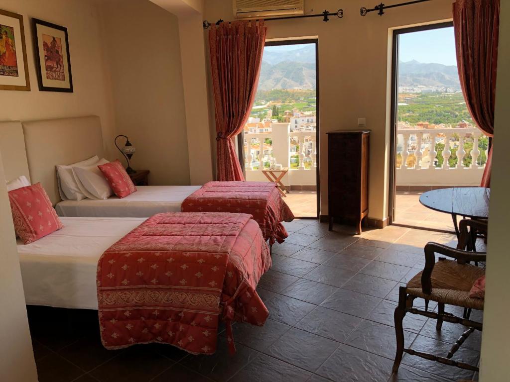 a hotel room with two beds and a large window at Hostal Avalon in Nerja