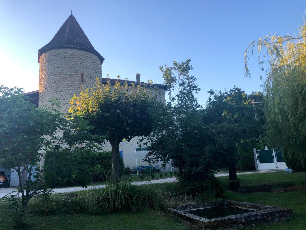 a building with a tower and trees in a yard at La Saônette in Lens-Lestang