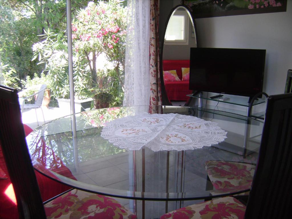 une table en verre dans le salon avec une fenêtre dans l'établissement Le Mazet du Thym, à Restinclières