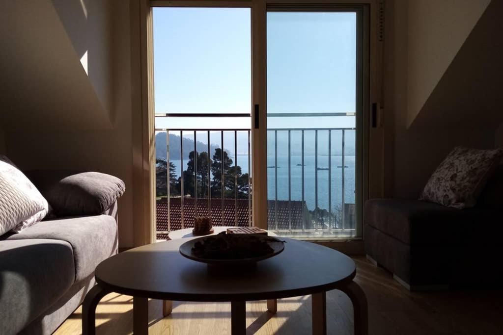 een woonkamer met een tafel en een groot raam bij Apartamento Aldara a escasos metros de la playa in Samieira