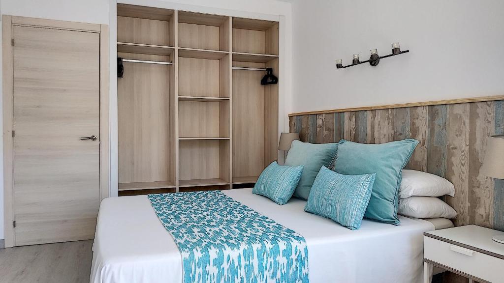 een slaapkamer met een bed met blauwe kussens bij Apartamentos Las Palmeras in Palmanova