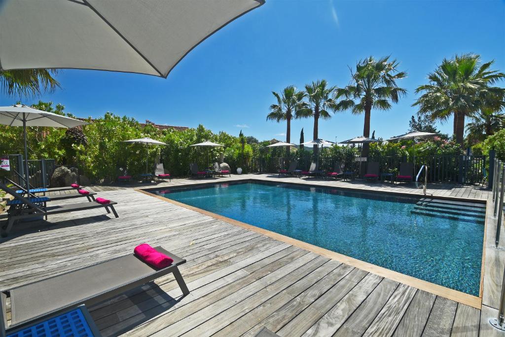 een zwembad met een houten terras met een bank en een parasol bij Golfe Hotel in Porto-Vecchio