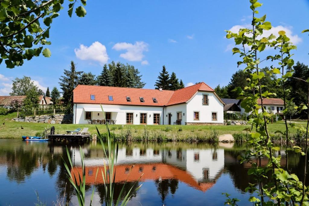 a white house with a red roof next to a lake at Landhaus Litschau in Litschau