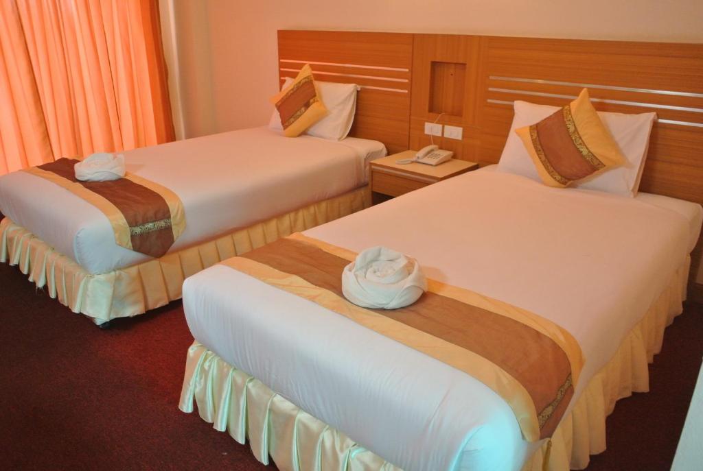 a hotel room with two beds with towels on them at Chaikana Thani Hotel in Phatthalung