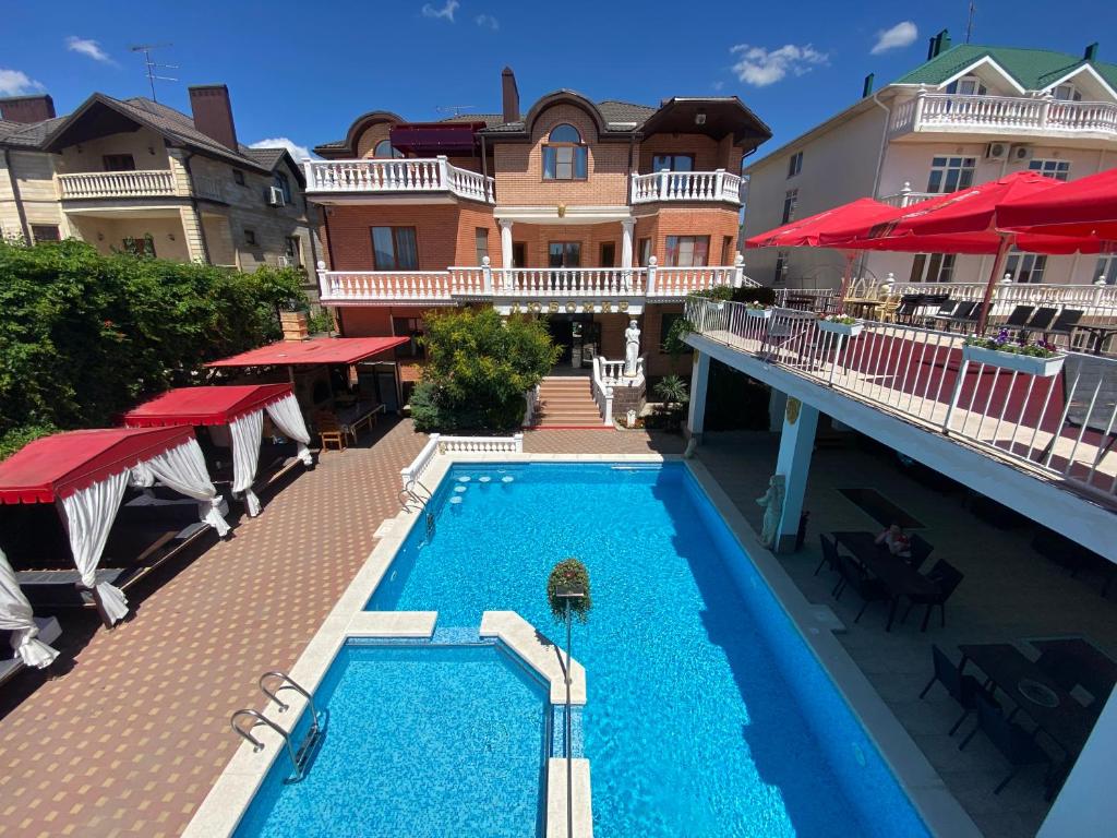 a swimming pool in front of a building with red umbrellas at Villa Lubomir in Vityazevo