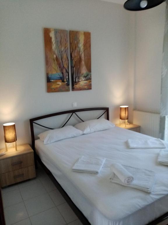 a bedroom with a white bed with two lamps at Deaspoina Apartments in Nea Roda
