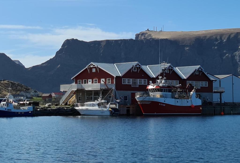 two boats are docked in the water near a house at Bensvik Brygge in Værøy