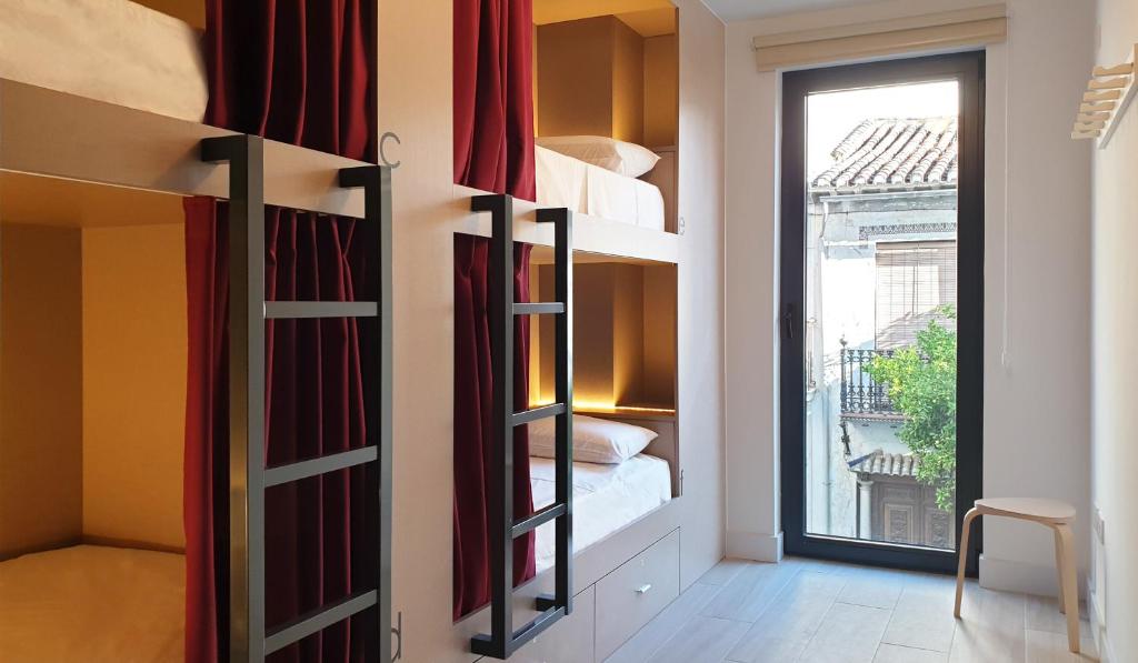 um quarto com beliches num quarto com uma janela em Broz Hostel em Granada
