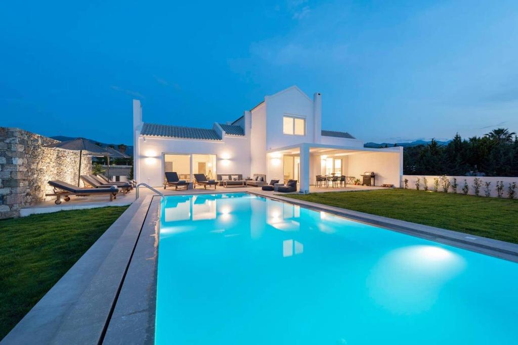 a villa with a swimming pool at night at Melia Villa, Kos Island in Kos