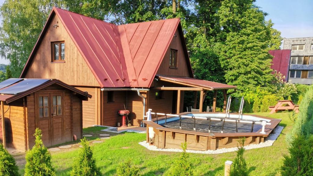 a house with a red roof and a hot tub at Chata Osmička in Zlaté Hory