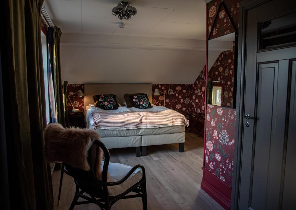 a bedroom with a bed and a chair and a mirror at Villa Göta in Forsvik