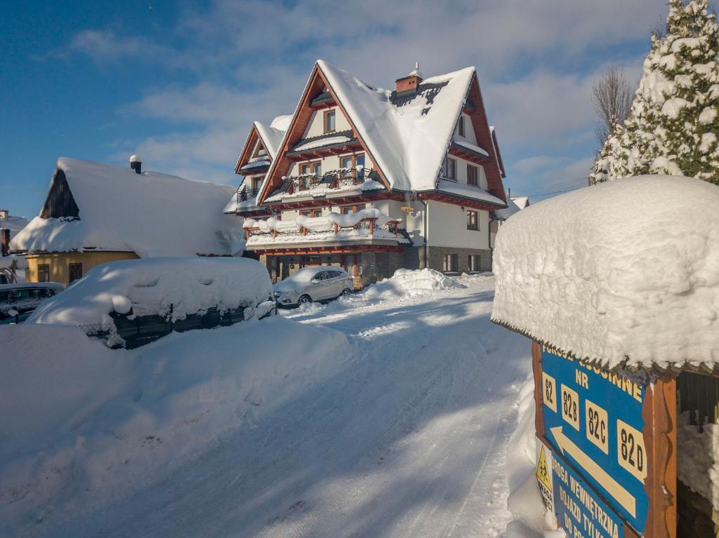 ein schneebedecktes Haus mit in der Einfahrt geparkten Autos in der Unterkunft MC82 - Anna Łukaszczyk in Małe Ciche