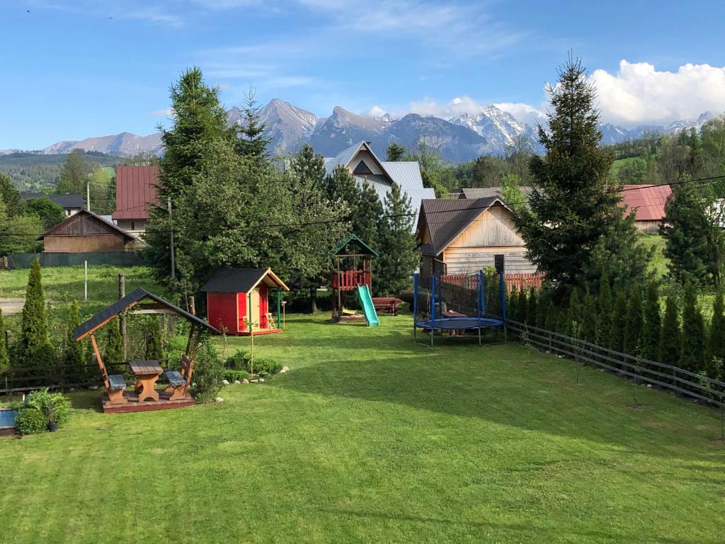 a yard with a playground with mountains in the background at Dom Wypoczynkowy U Kasi in Jurgów