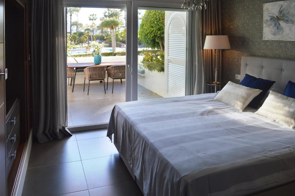 1 dormitorio con cama, mesa y balcón en Alcazaba Beach Luxury Apartment02 Estepona, en Estepona