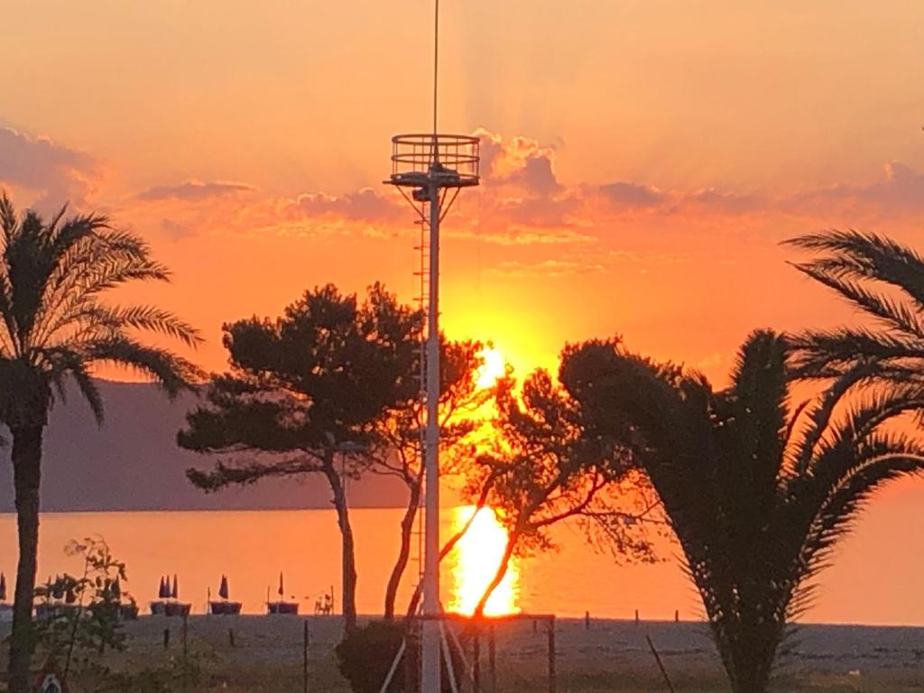 a sunset with palm trees and a cell phone tower at Portorosa Vista Mare in Furnari