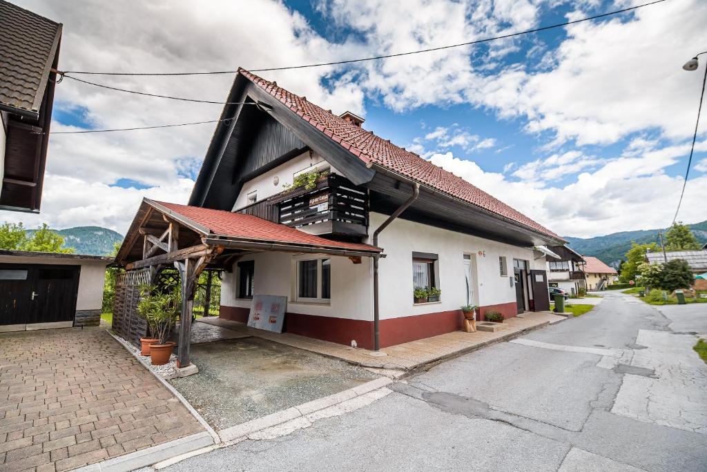 a white house with a red roof on a street at Home away from home in Bohinj