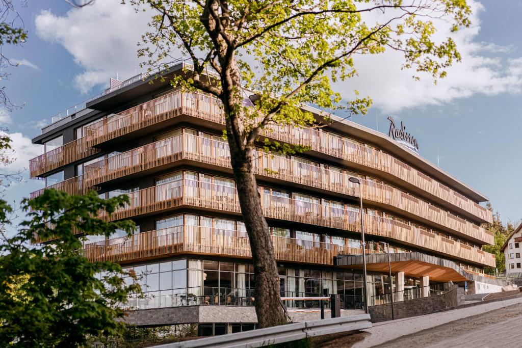un edificio con un árbol delante de él en Radisson Hotel Szklarska Poręba, en Szklarska Poręba