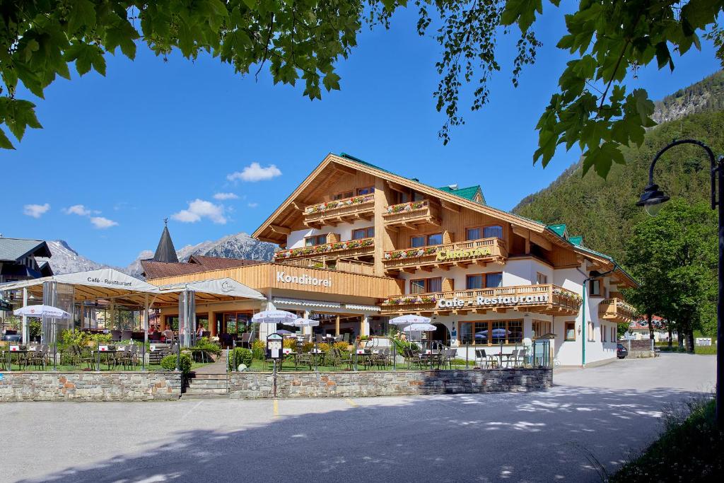 ein großes Gebäude mit Tischen und Stühlen davor in der Unterkunft Hotel Christina - Ihr kleinstes 4* Hotel am Achensee in Pertisau