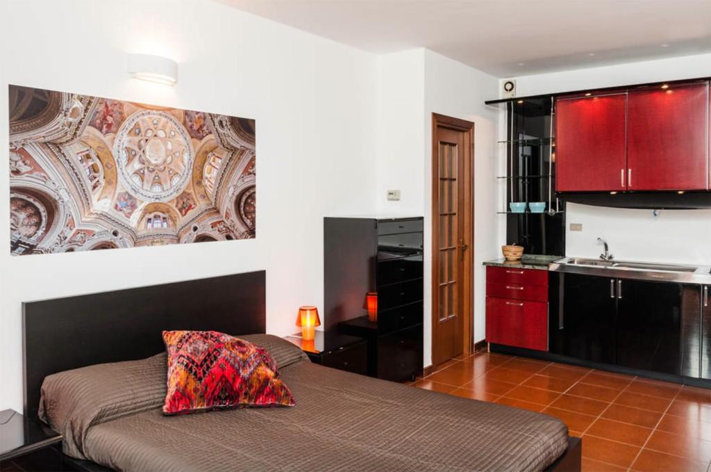 ein Schlafzimmer mit einem Bett und eine Küche mit roten Schränken in der Unterkunft Studio S. Tommaso a Piazza Castello by Wonderful Italy in Turin