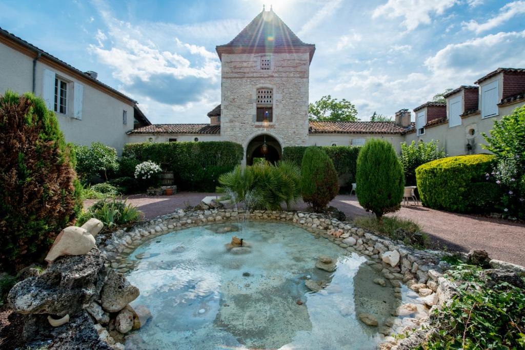 Sérignac-sur-GaronneにあるLogis Hotel Le Prince Noirの建物前の小さな池のある庭園