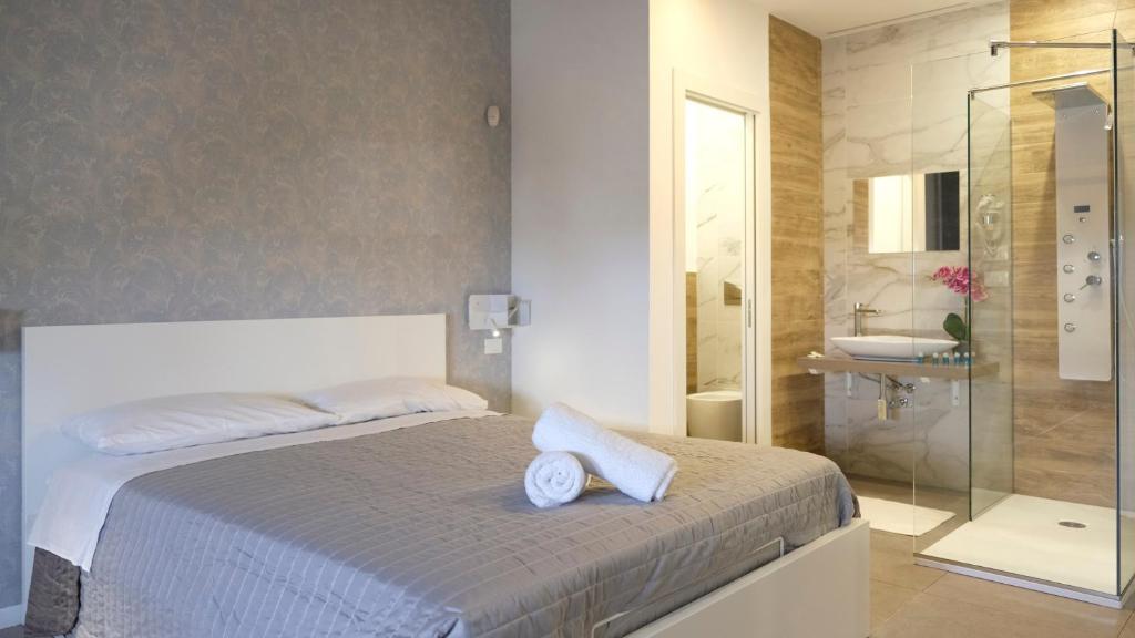 1 dormitorio con 1 cama y ducha acristalada en Le Saline Rooms Marzamemi, en Marzamemi