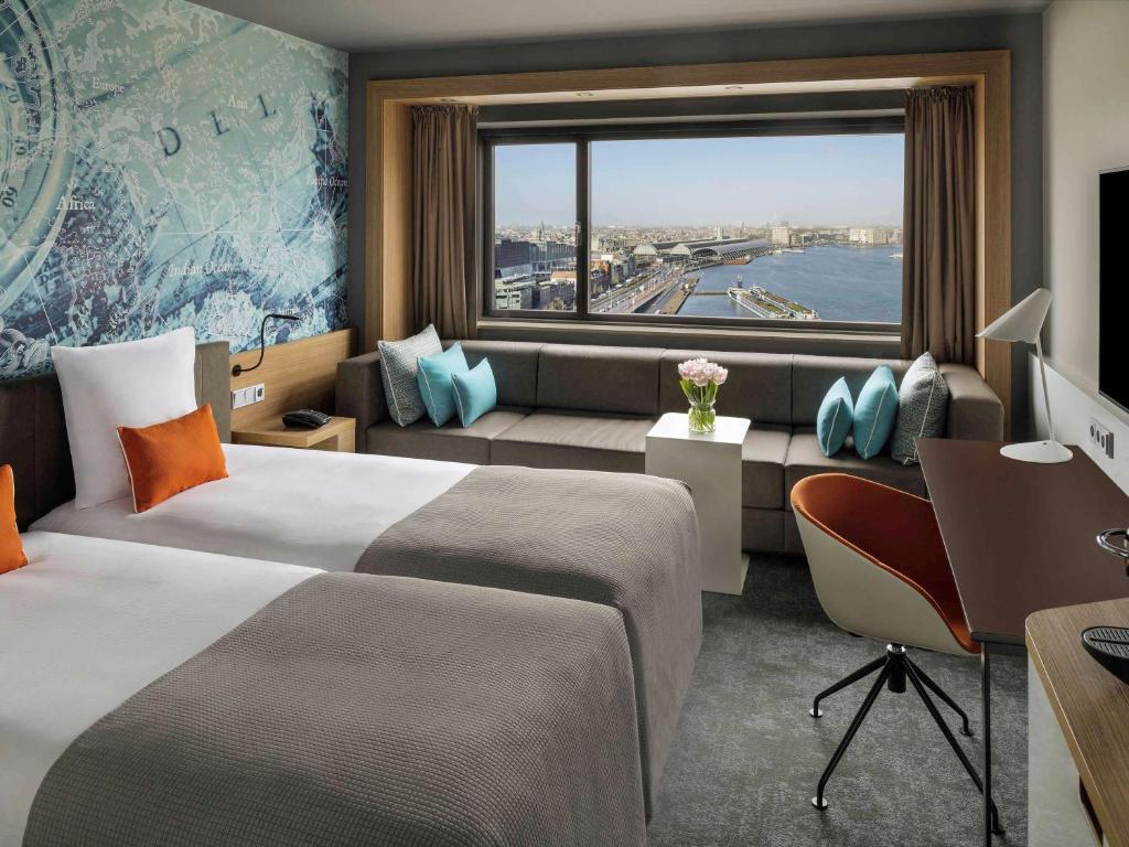 une chambre d'hôtel avec deux lits, un bureau et une fenêtre dans l'établissement Mövenpick Hotel Amsterdam City Centre, à Amsterdam