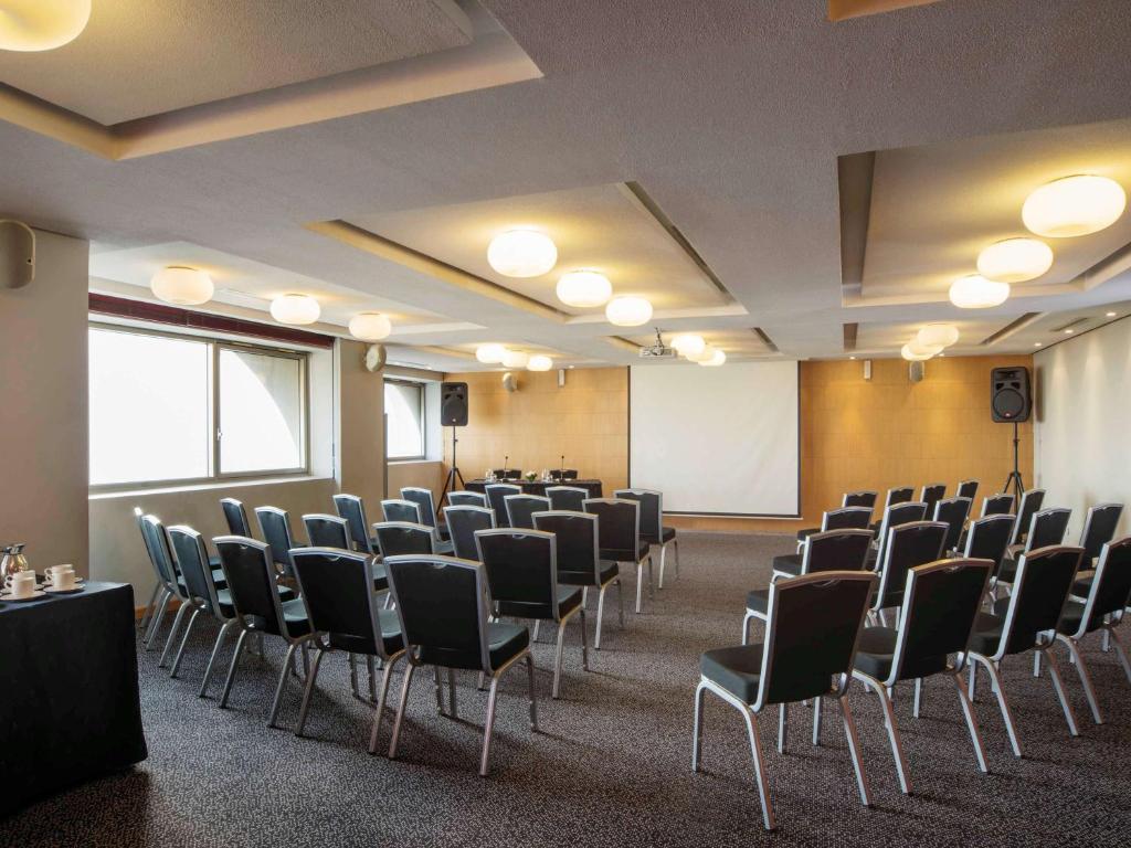 a conference room with chairs and a white screen at Mövenpick Hotel Casablanca in Casablanca