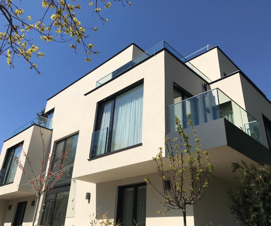 a white house with black windows and trees at Premium Green Apartments Vienna in Vienna