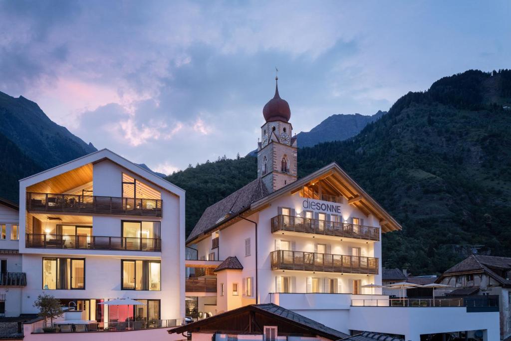 un edificio con una torre de reloj encima en Alpin & Stylehotel Die Sonne, en Parcines