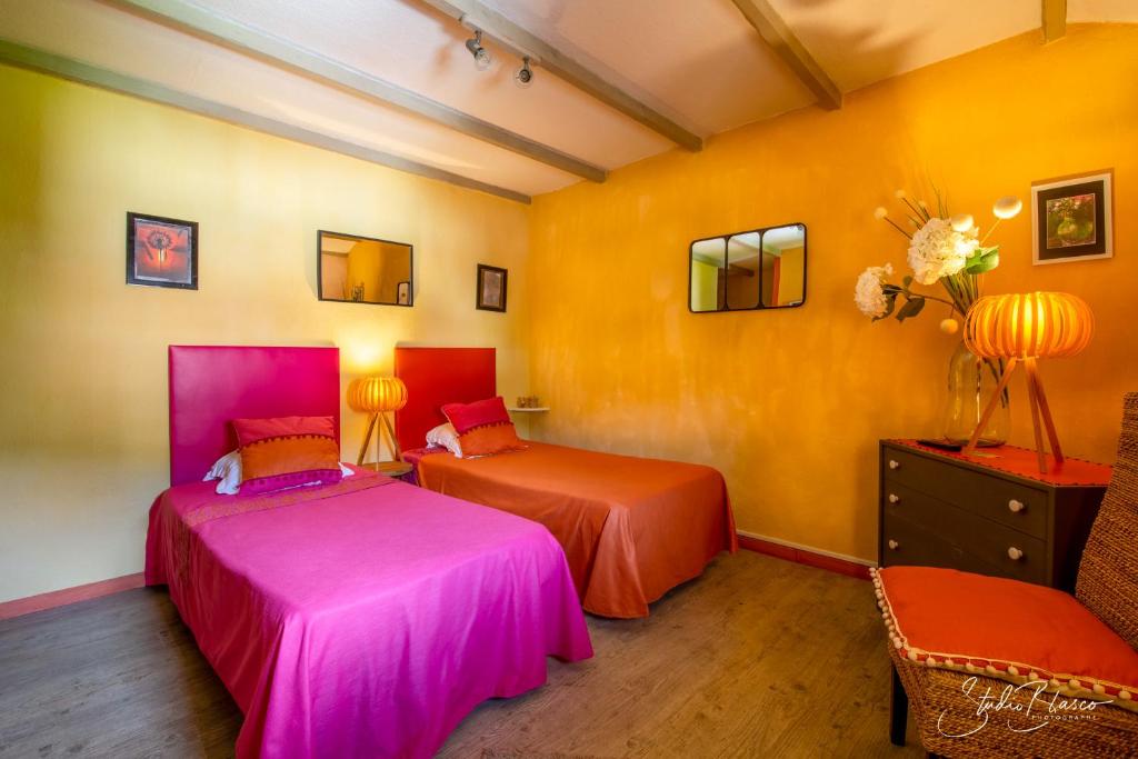 two beds in a room with orange and pink at Le Relais Des Dentelles in Beaumes-de-Venise