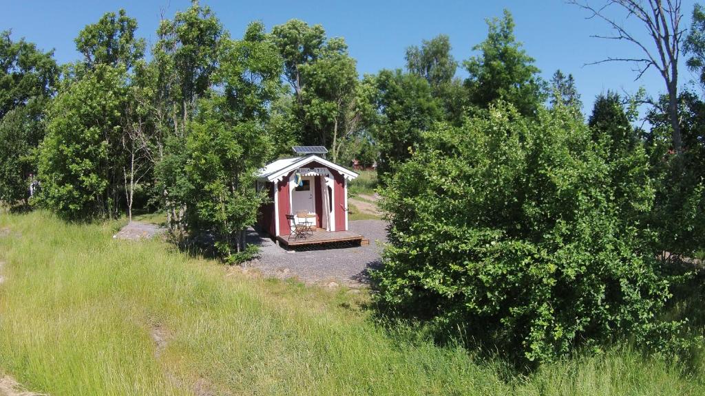 東哈爾馬的住宿－Liten enklare klimatsmart stuga i Roslagen，田野中间的一个小红棚