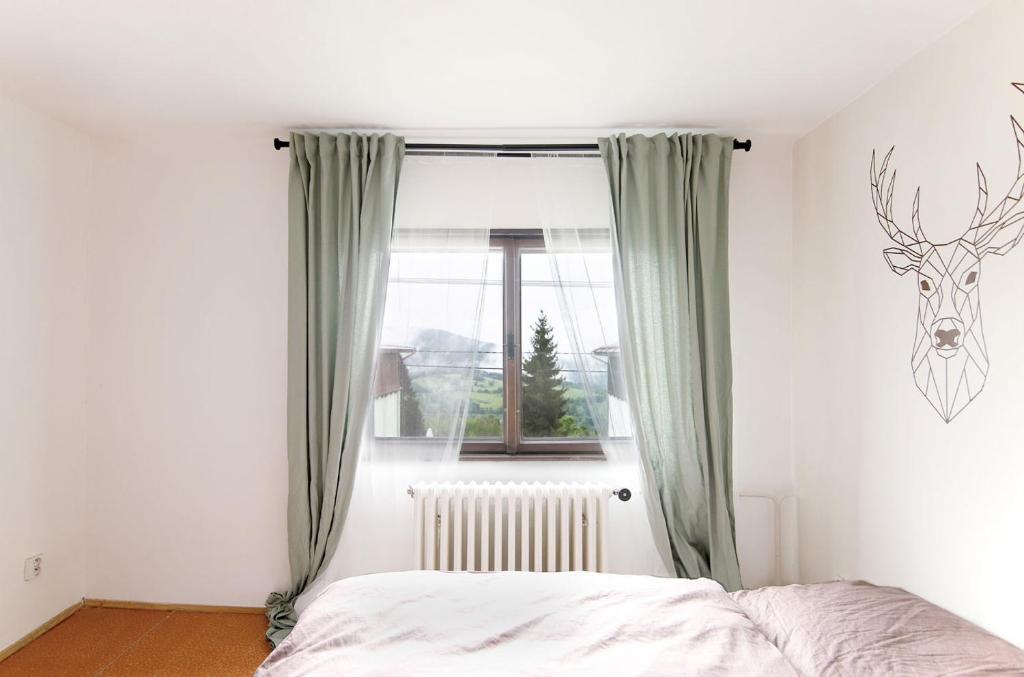 Dormitorio con ventana con cabeza de ciervo en la pared en Horská chata NATURA Nové Město en Nové Město