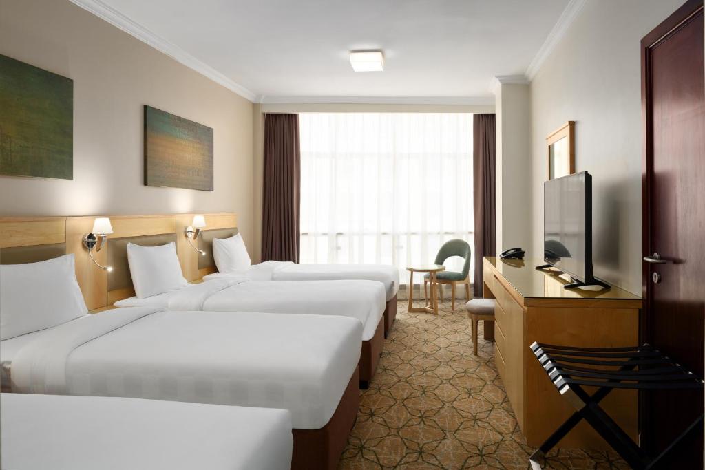 a hotel room with four beds and a flat screen tv at Saja Al Madinah in Al Madinah