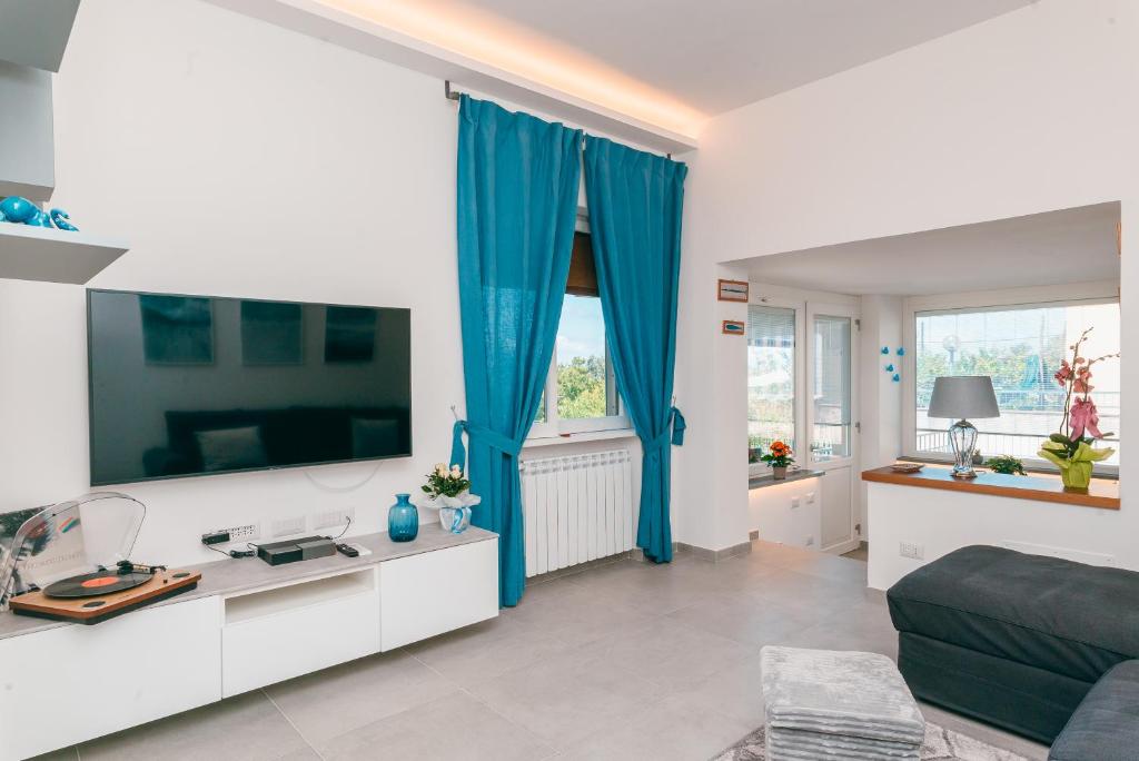 uma sala de estar com uma televisão grande e cortinas azuis em Oltremare Sorrento coast apartment em Piano di Sorrento