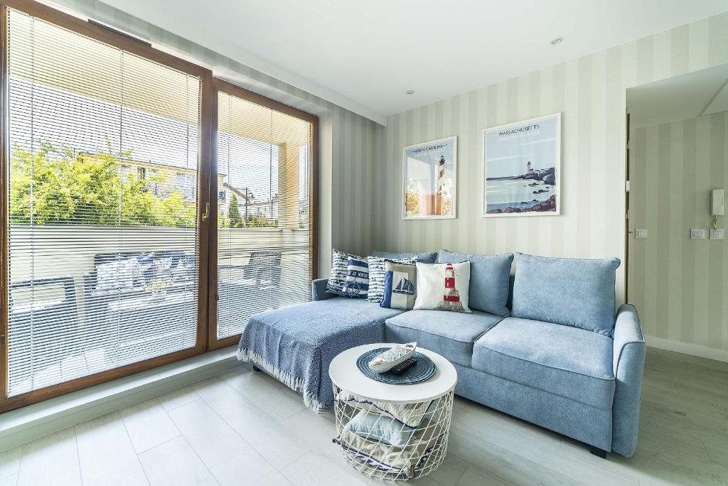a living room with a blue couch and a large window at Surf Apart in Władysławowo
