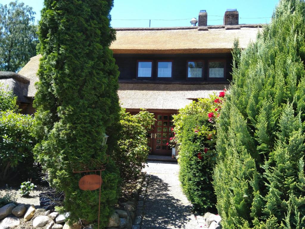 un jardin avec des arbres et des buissons en face d'une maison dans l'établissement Bei Ulbrichs Hotel garni & Catering, à Soltau