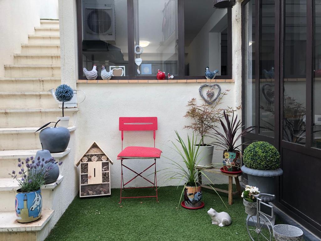 une chaise rouge assise sur le côté d'une maison ornée de plantes dans l'établissement Ô 36 Rempart Sud B&B, à Aigues-Mortes