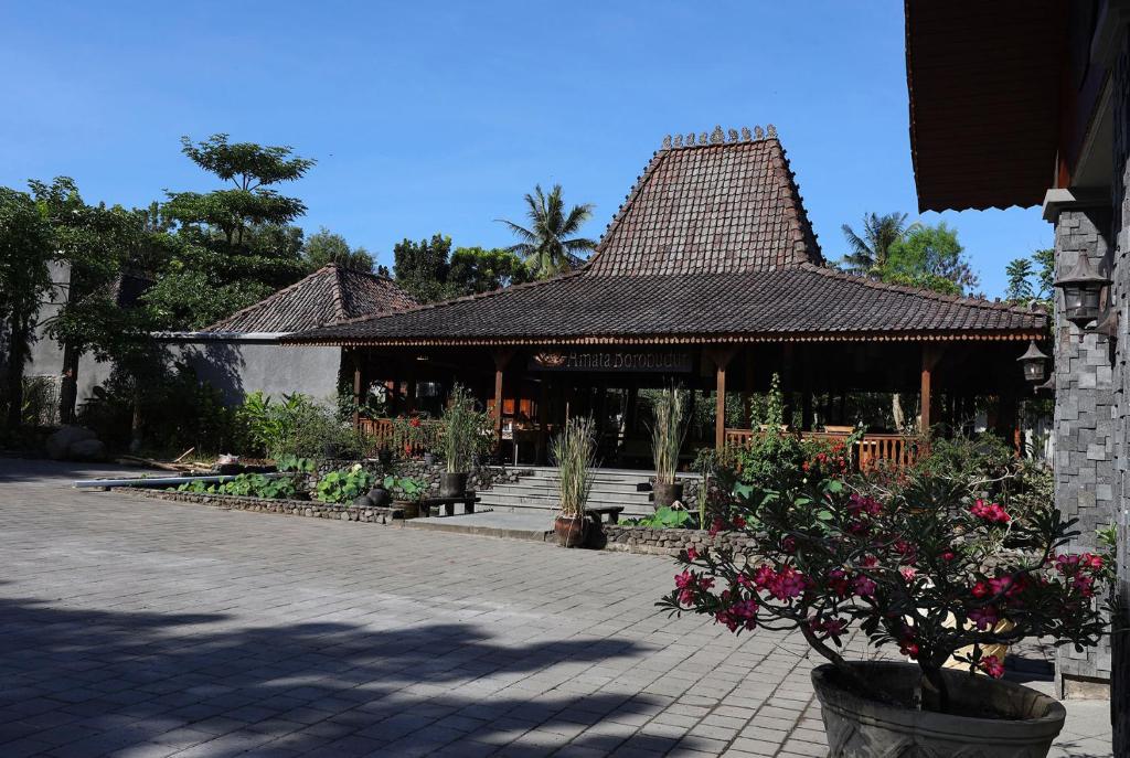 un bâtiment avec un toit fleuri dans une cour dans l'établissement Amata Borobudur Resort, à Borobudur