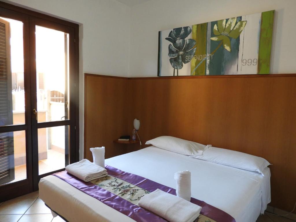 a bedroom with a white bed and a large window at B&B Isola in Fiumicino