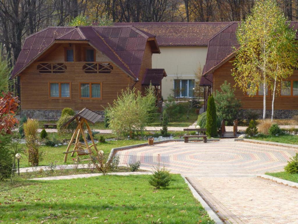 una casa con un patio con un parque infantil delante de ella en Erney Laz Hotel, en Shayan